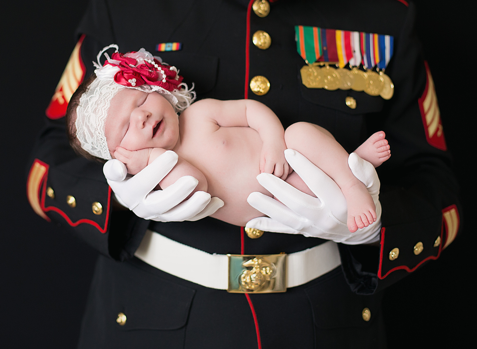 Baby girl smiles while her father, a Marine, holds her Newborn Photographer Jacksonville NC