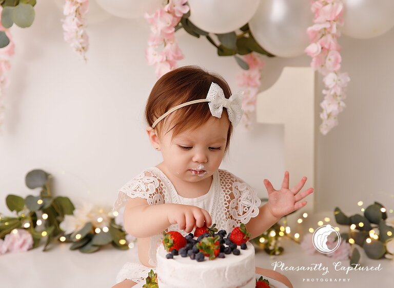 Little girl picking a berry off of her birthday cake photographer jacksonville nc