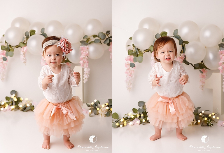 little girl smiling in front of balloons and flowers Birthday Photographer Jacksonville NC