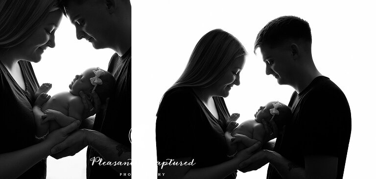 Black and white of mom and dad holding baby and looking down at her - Jacksonville North Carolina Newborn Photography