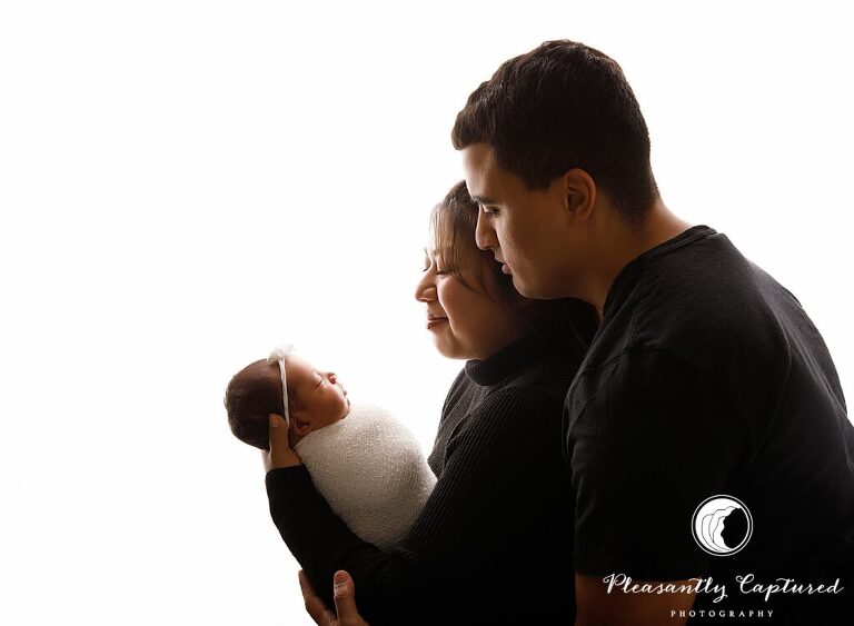 Backlit photo of new parents holding their newborn daughter - richlands nc Newborn photographer