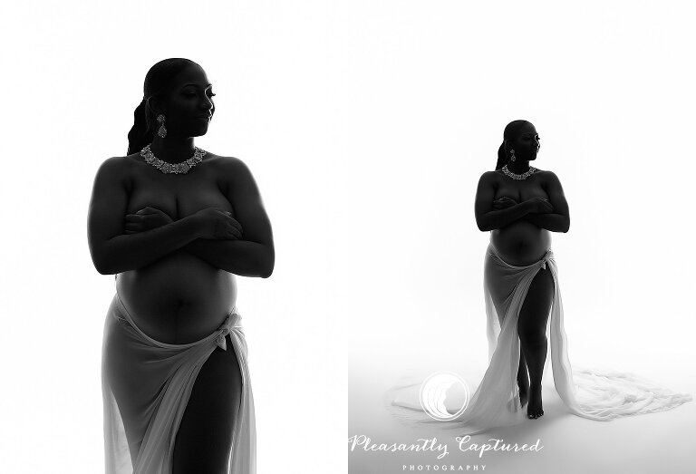 Silhouette of expecting mother in white fabric at indoor maternity shoot