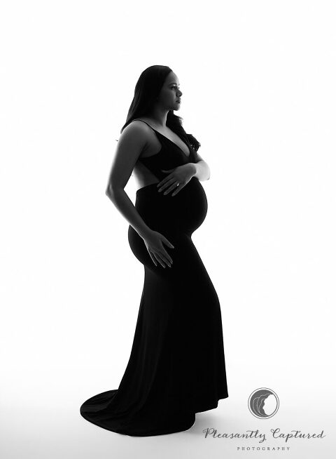 Beautiful mother to be in black and white photo in black dress touching pregnant belly | photographer near wilmington and newborn nc