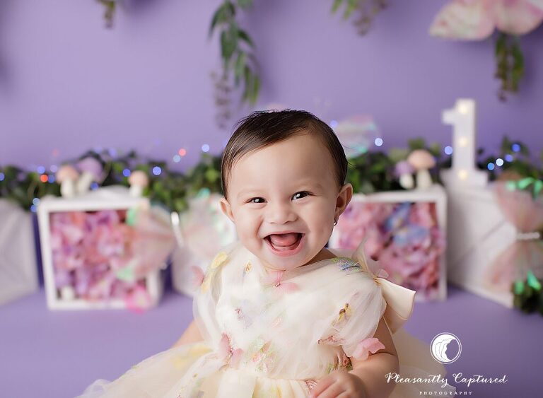 First birthday portraits with a whimsical butterfly garden theme by Jacksonville, NC cake smash photographer Pleasantly Captured Photography.
