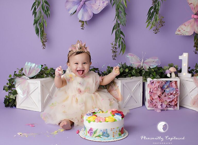 Baby girl enjoying colorful frosting during a first birthday cake smash session in Jacksonville, NC.