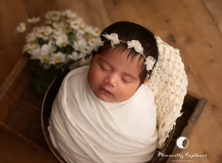 Jacksonville, NC newborn photographer capturing a peaceful baby girl wrapped in white during a newborn mini session.