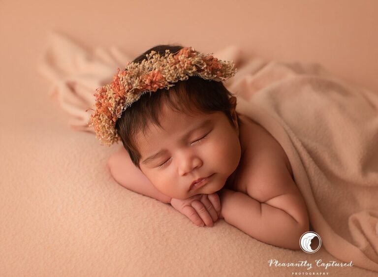 Simple table pose from a newborn mini session in Jacksonville, NC featuring a sleeping baby girl with soft peach tones.