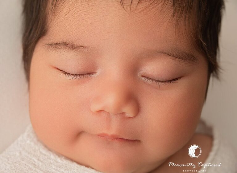 Close-up newborn portrait showing baby girl’s tiny eyelashes and peaceful sleeping face during a Jacksonville, NC newborn session.